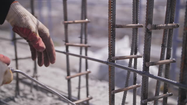 builder fixes the reinforcement on the construction site with wire