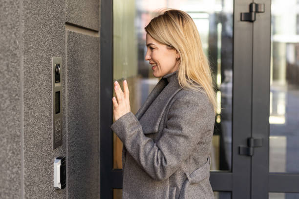 istock Happy woman ringing on doorbell at building entrance. Using intercom 1479454334