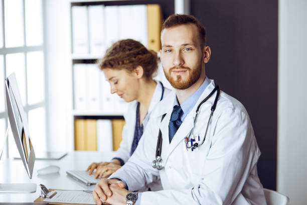 istock Red-bearded doctor with female colleague discussing current disease therapy while sitting at working place in clinic. Team work in medicine 1479454432