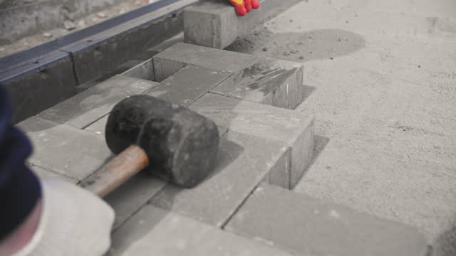 builder lays paving stones on the street