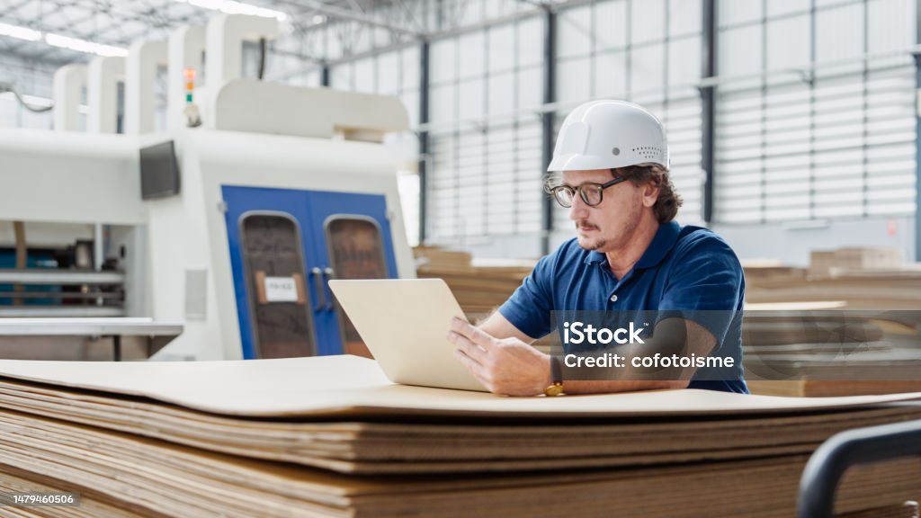 Professional Engineer checking quality control, and Manufacturing Operations Professional Engineer using laptop checking quality control, and Manufacturing Operations in the paper packaging factory Manufacturing Stock Photo