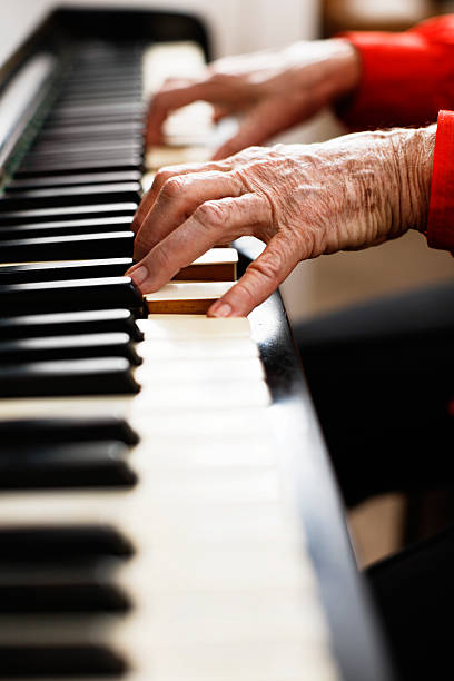 istock Looking across keyboard to wrinkled hands playing piano 147946125