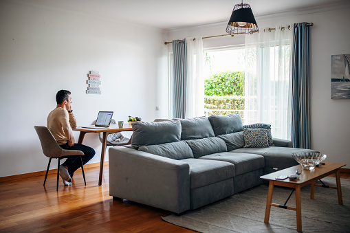 Man on the phone using laptop for work at home.