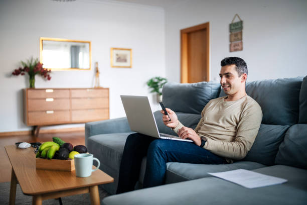 istock Man sitting on sofa and using laptop at home. 1479462157