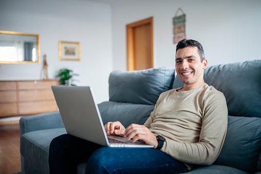 Portrait of smiling man with laptop working from home.