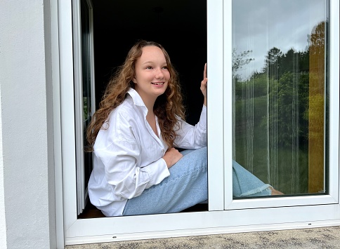 online study sitting at home quarantine girl in a white blouse looks out the window. High quality photo