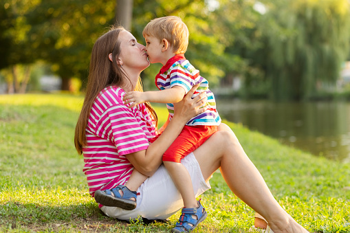 Mother having rest with her little kid son together outdoors in park. Love family concept