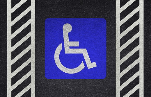 Wheelchair sign on the pavement. Wheelchair Handicap Sign on dark asphalt road street background- handicap parking place