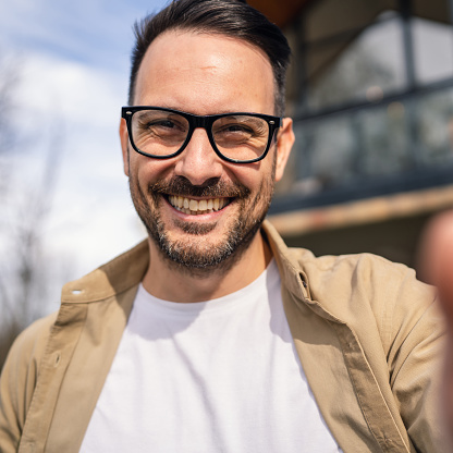 One modern adult caucasian man portrait of male with beard and eyeglasses happy confident at home self portrait selfie UGC user generated content