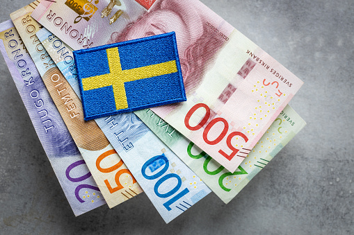 Sweden flag lying on a bundle of swedish kronas, Currency of Sweden, business and financial concept