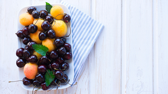 A plate with apricots and cherries