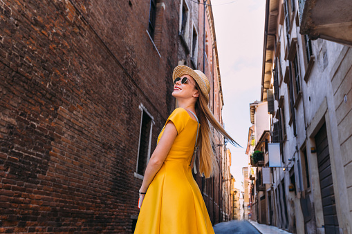 stylish girls in a yellow dress and sunglasses looking at the building and smile. street, city, building
