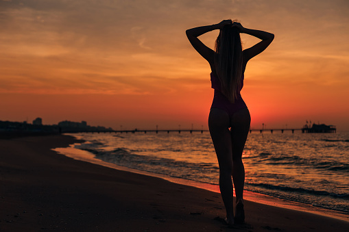 silhouette of a girl with long hair admiring the sunset and sea