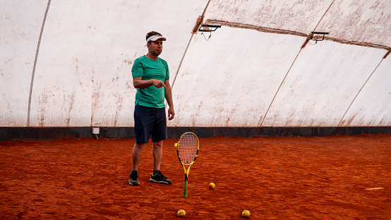 tennis coach is showing tennis racket and teaching horizontal kids tennis club still
