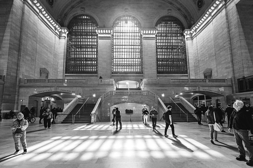 New York City, NY, USA — April 2, 2023: Commuters walk to and from trains at Grand Central Station with sun pouring in on