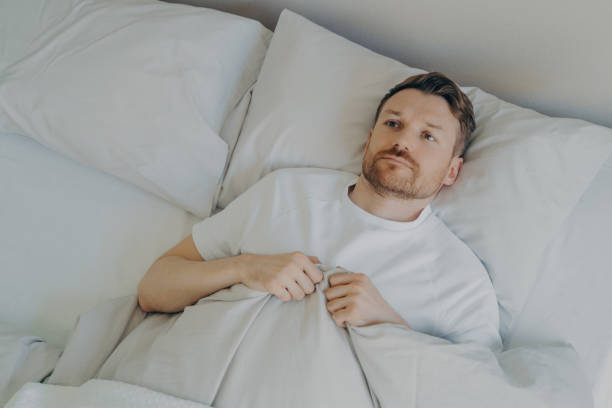 istock Lonely upset young bearded man lying in bed with open eyes 1479485237