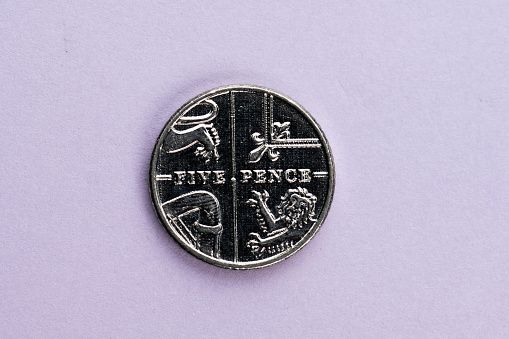 British five pence coin on purple background.