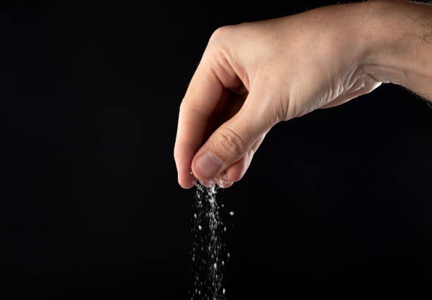 istock Hand sprinkling salt, salt on a black background. 1479492371