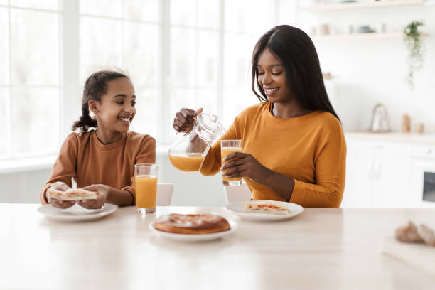 istock Black Mom And Daughter Drinking Fresh Juice Sitting In Kitchen 1479493380