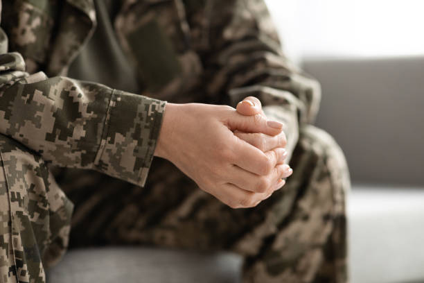 istock Unrecognizable Female In Camouflage Uniform Sitting On Couch With Clasped Hands 1479494149