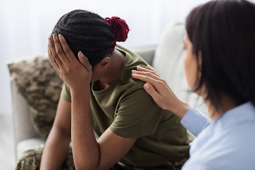 Mujer psicoterapeuta consolando y apoyando a una soldado negra con trastorno de estrés postraumático, primer plano photo