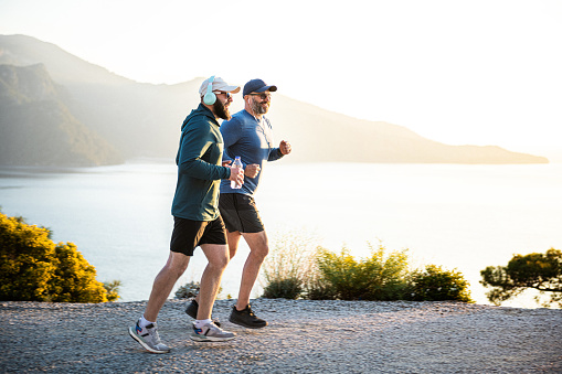 Two middle aged man jogging in mountains at sunset