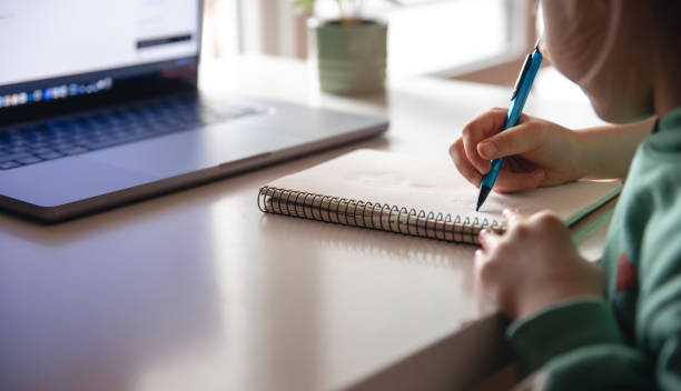 istock A little girl writes with a pen in a notebook, does her homework. 1479499591