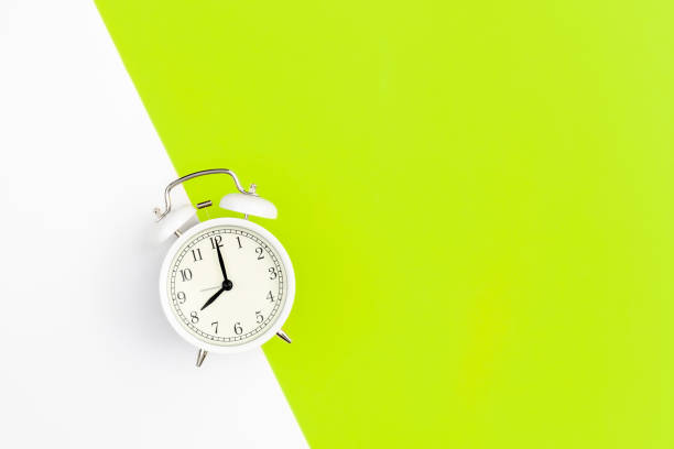 istock White alarm clock on a white and green background, flat lay. 1479500004