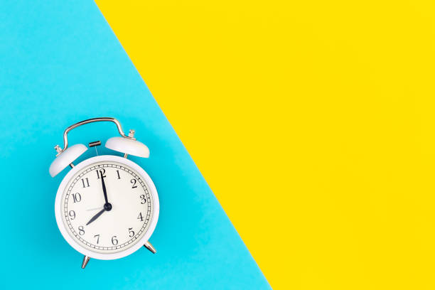 istock White alarm clock on a blue and yellow background, flat lay. 1479500007