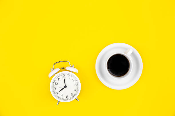 istock Alarm clock and a cup of coffee on a yellow background, top view. 1479501880