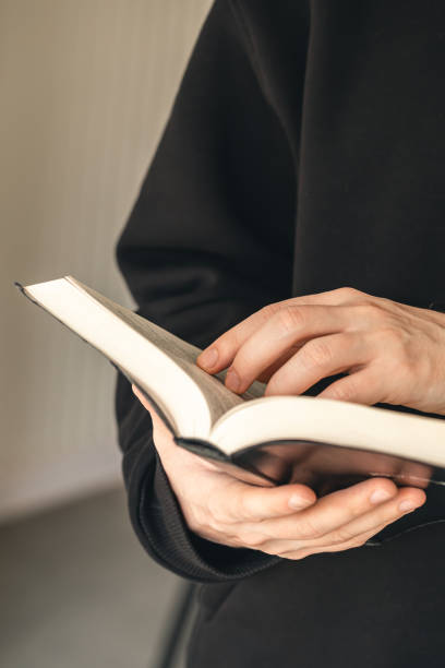 Open holy book Bible in male hands, close-up, the concept of Christianity, faith in God.