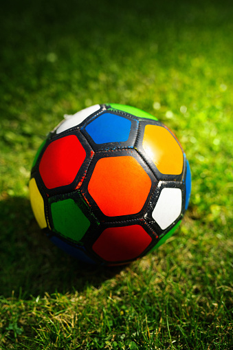 Closeup side view of a multi colored soccer ball on a freshly cut pitch grass