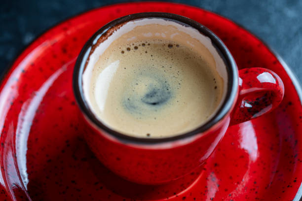 istock Fresh aromatic morning coffee in red cup on a black background, closeup 1479506875