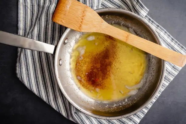 Overhead view of browned butter in a frying pan on a kitchen towel