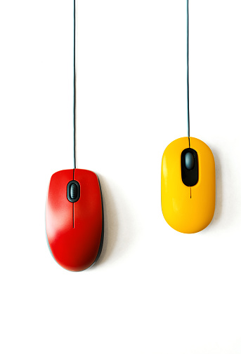 Closeup top view of red and yellow computer mice over white background.