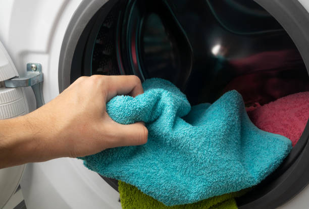 istock Hand and puts the laundry into the washing machine. 1479514068