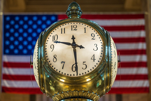 Looking up at the Tiffany's Clock in Grand Central Station with the American Flag in the background. New York City, NY. USA