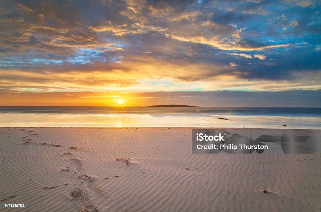 Long exposure seascape of golden sunset reflecting on the beach Long exposure seascape of golden sunset reflecting on the beach. East Coast, Australia. Majestic Stock Photo