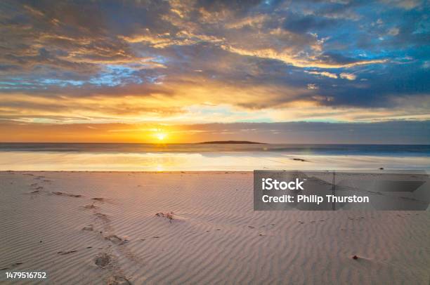 Long Exposure Seascape Of Golden Sunset Reflecting On The Beach Stock Photo - Download Image Now