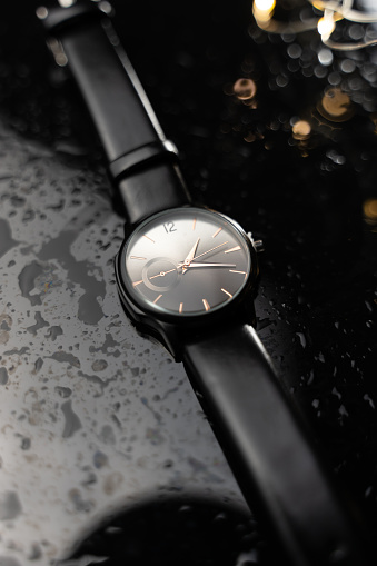 wrist watch on the black glass table. stylish watch photo.  water drops on the table. luxury watch. clock