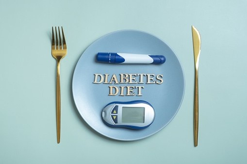 Diabetes Diet text. Glucometer and fork in plate on colored background flat lay, top view. Diet for Diabetics Minimal concept.