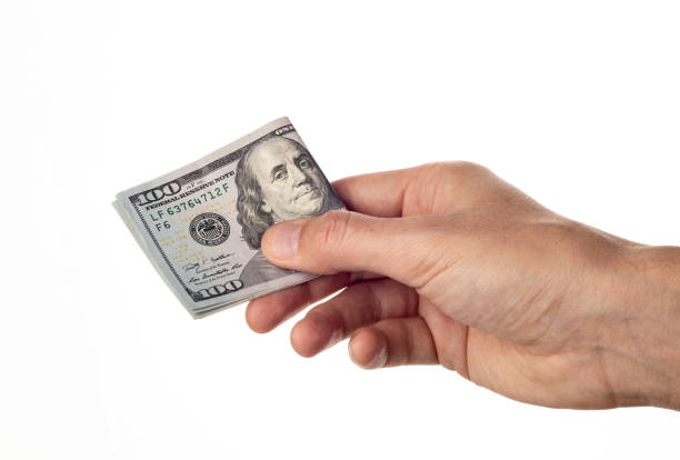 istock Man's hand giving 100 dollar bills isolated on white background. 1479518052