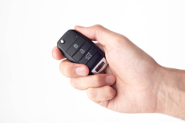 A man's hand holds the car key isolated on a white background close up.