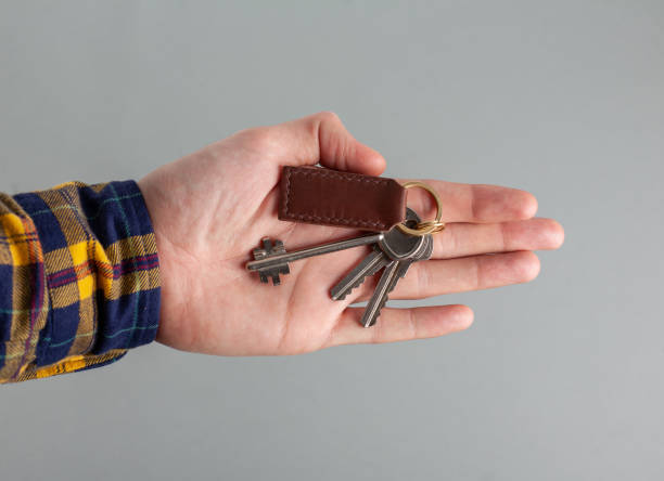 istock Keys with a brown leather keychain in hand on a grey background. 1479519669