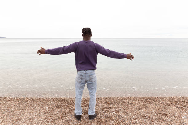 istock Afro man with open arms on the beach 1479520568