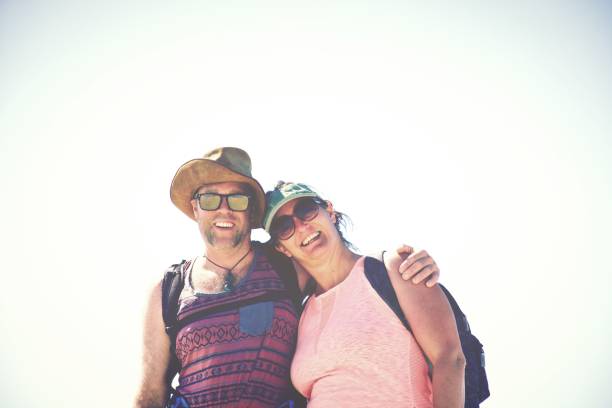 A portrait of a man and a women smiling to the camera in a sand dune background.