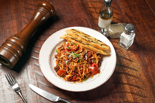 Spaghetti Bolognese with garlic bread served in dish isolated on wooden table top view of italian fast food
