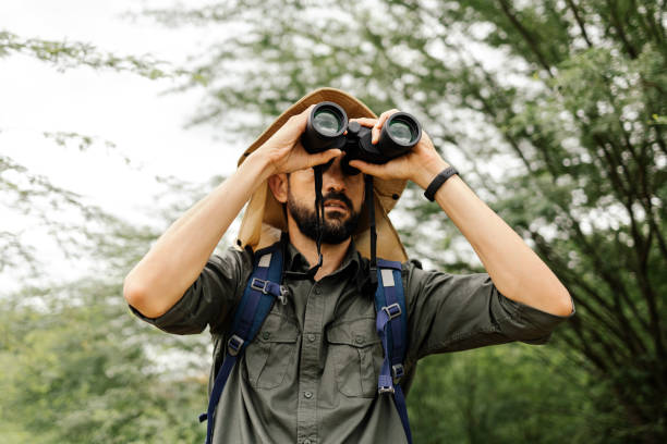 istock Hiker with backpack using binoculars in the wild. Field biologist or naturalist using binoculars to study wildlife or nature. 1479528393