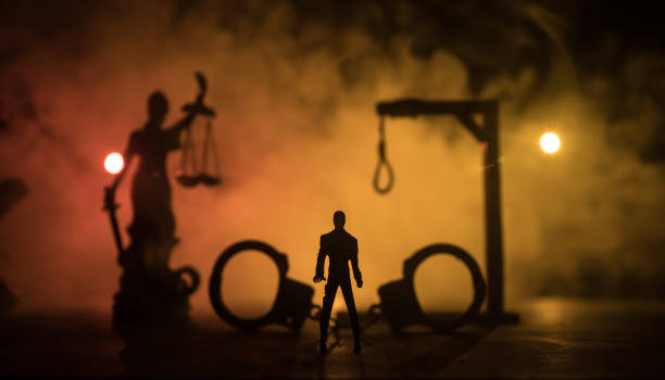 Execution concept. Death penalty electric chair miniature in selective focus inside old prison. Old prison bars cell lock. Creative artwork decoration. Electric chair scale model in the dark stock photo