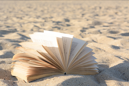 Open book on sandy beach, closeup view